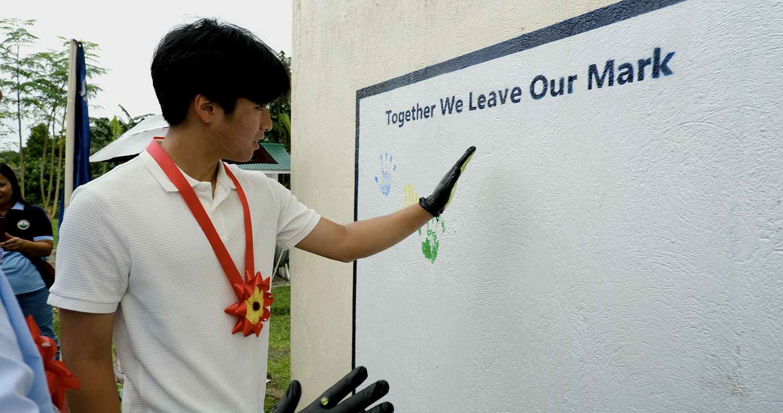 A student volunteer adds a handprint to the mural